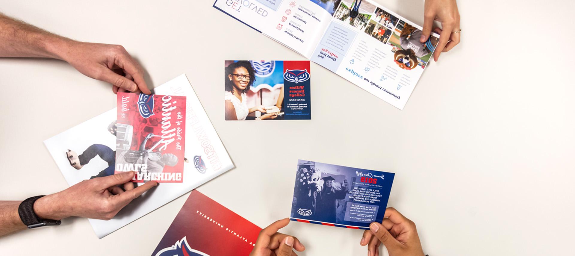 Hands holding cards, posters, magazines